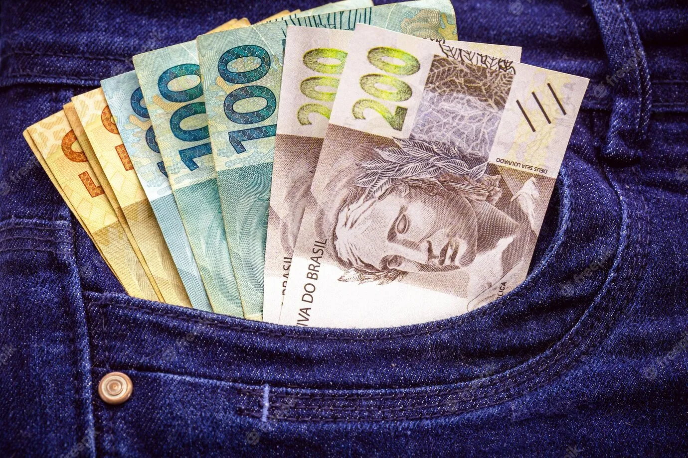 Cédulas de reais no bolso de uma calça jeans